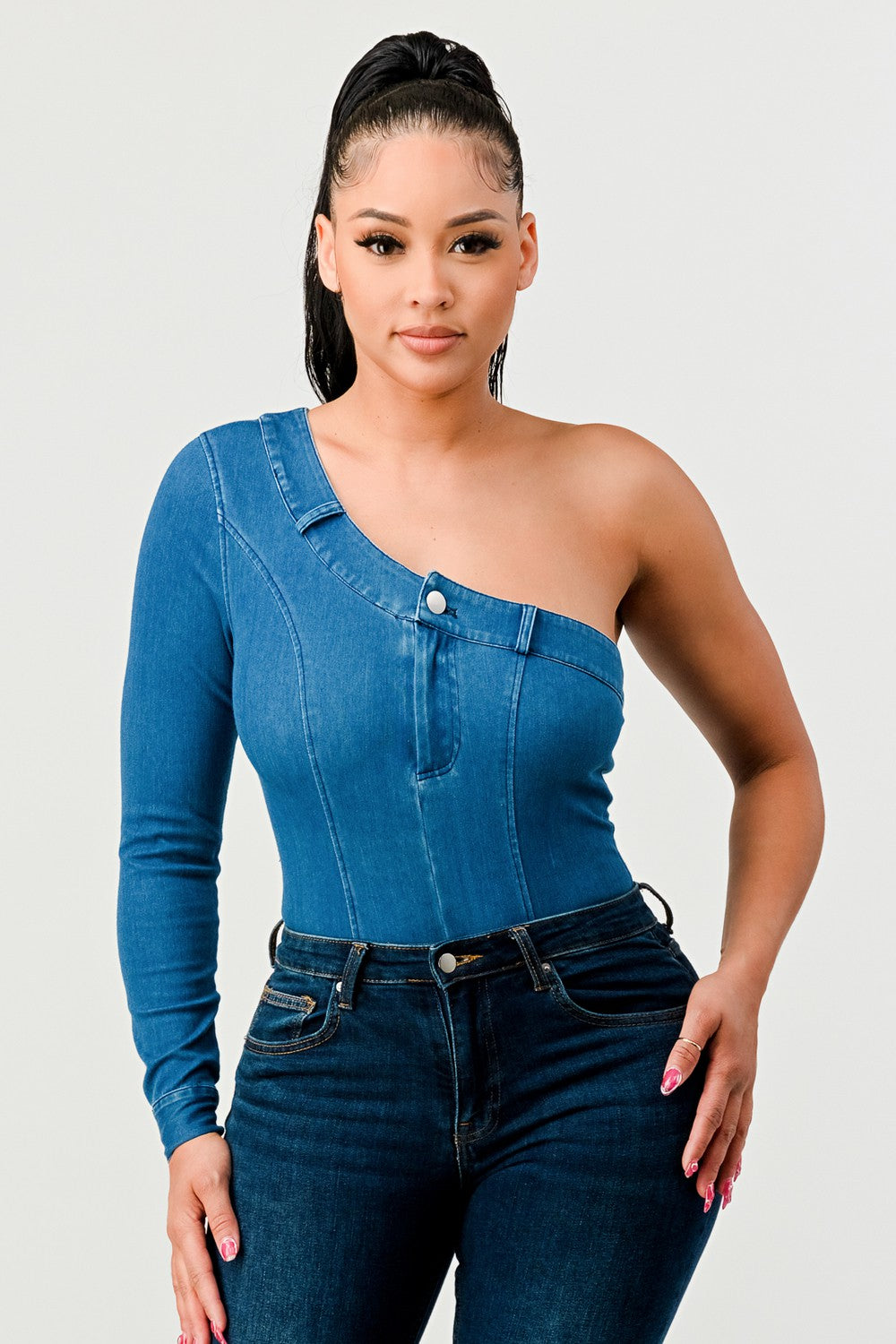 Woman wearing a blue one-shoulder top and jeans against a white background